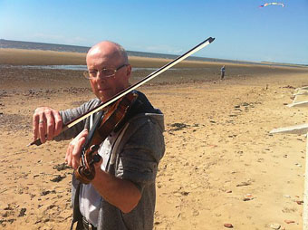 Richard playing violin on Crosby beach during the recording of BBC radio 4's WORD OF MOUTH - July 2014: Photo Credit: BBC